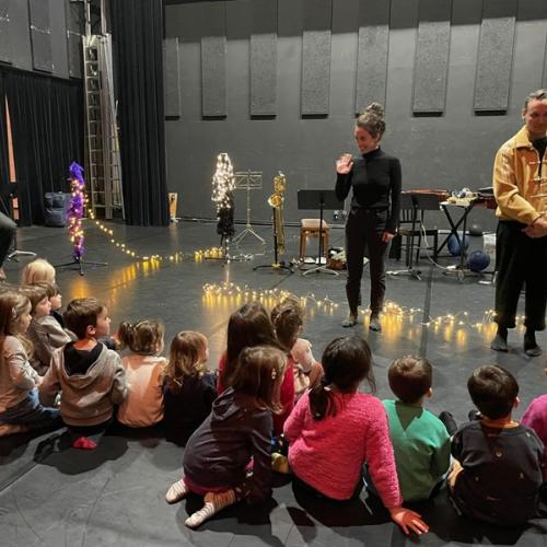 des enfants devant des artistes dans une salle de spectacle